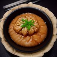 妖精动漫主编阿澈的肖像照，戴眼镜的年轻人在书架前微笑，背景是柔和的灯光